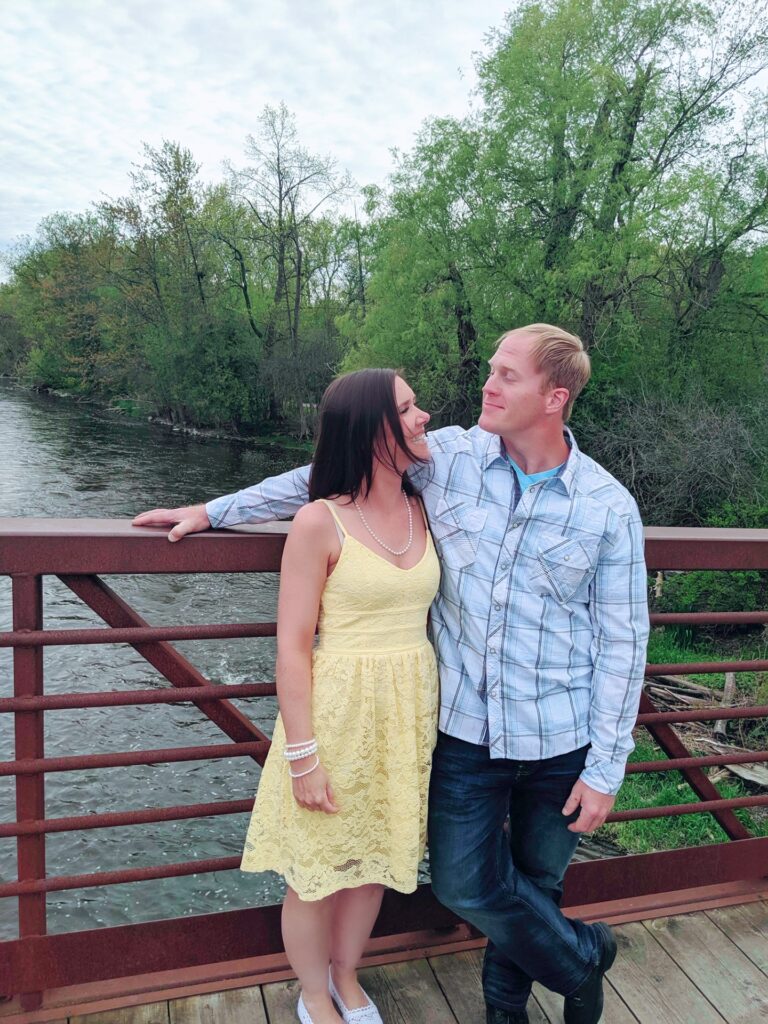 Aimee and her husband Dean standing on a bridge laughing