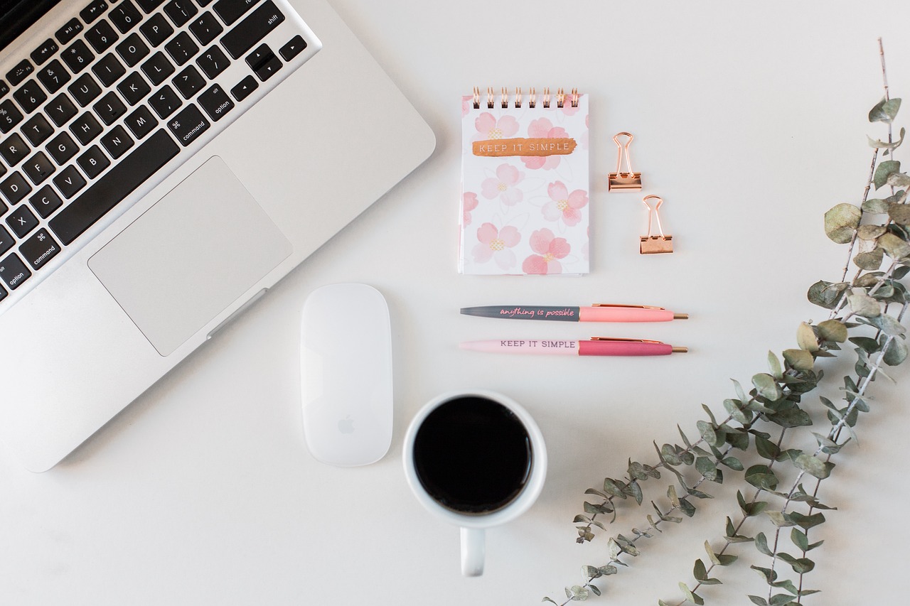 A laptop, notebook, and coffee on a table